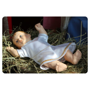 Ubrana figurka dzieciątka Jezus, leżąca w żłobie na sianie