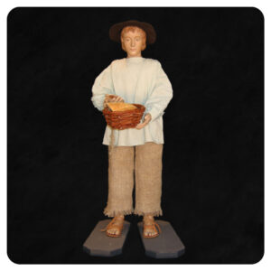 Pasterz w kapeluszu trzymający koszyk z darami. Figura do szopki bozonarodzeniowej